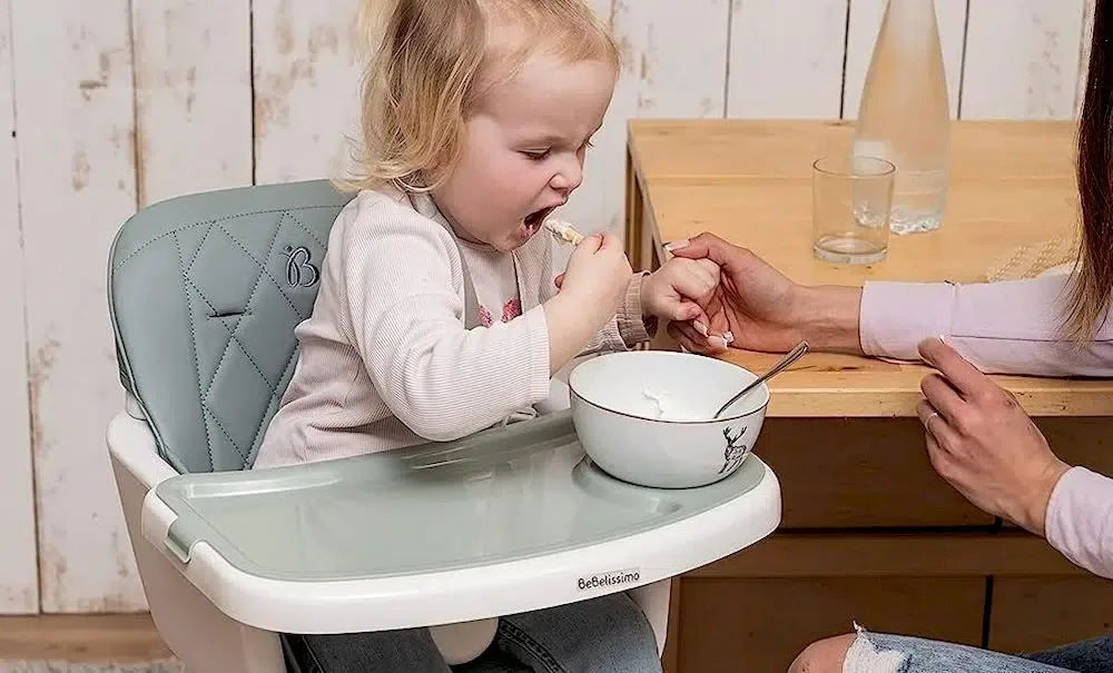 Une mère nourrissant son enfant assise sur une Chaise haute évolutive