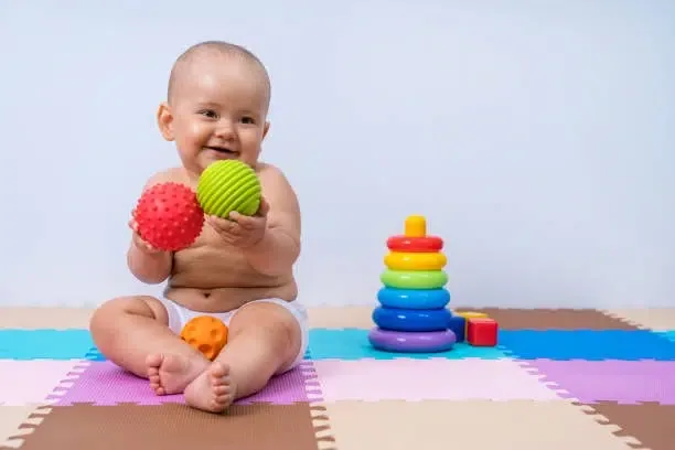 A toddler plays with rubber balls to develop hand motor skills
