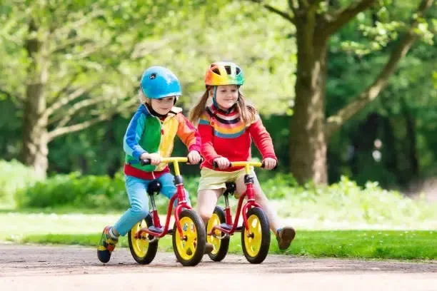 Enfants faisant du vélo d'équilibre : la draisienne, dans un parc ensoleillé